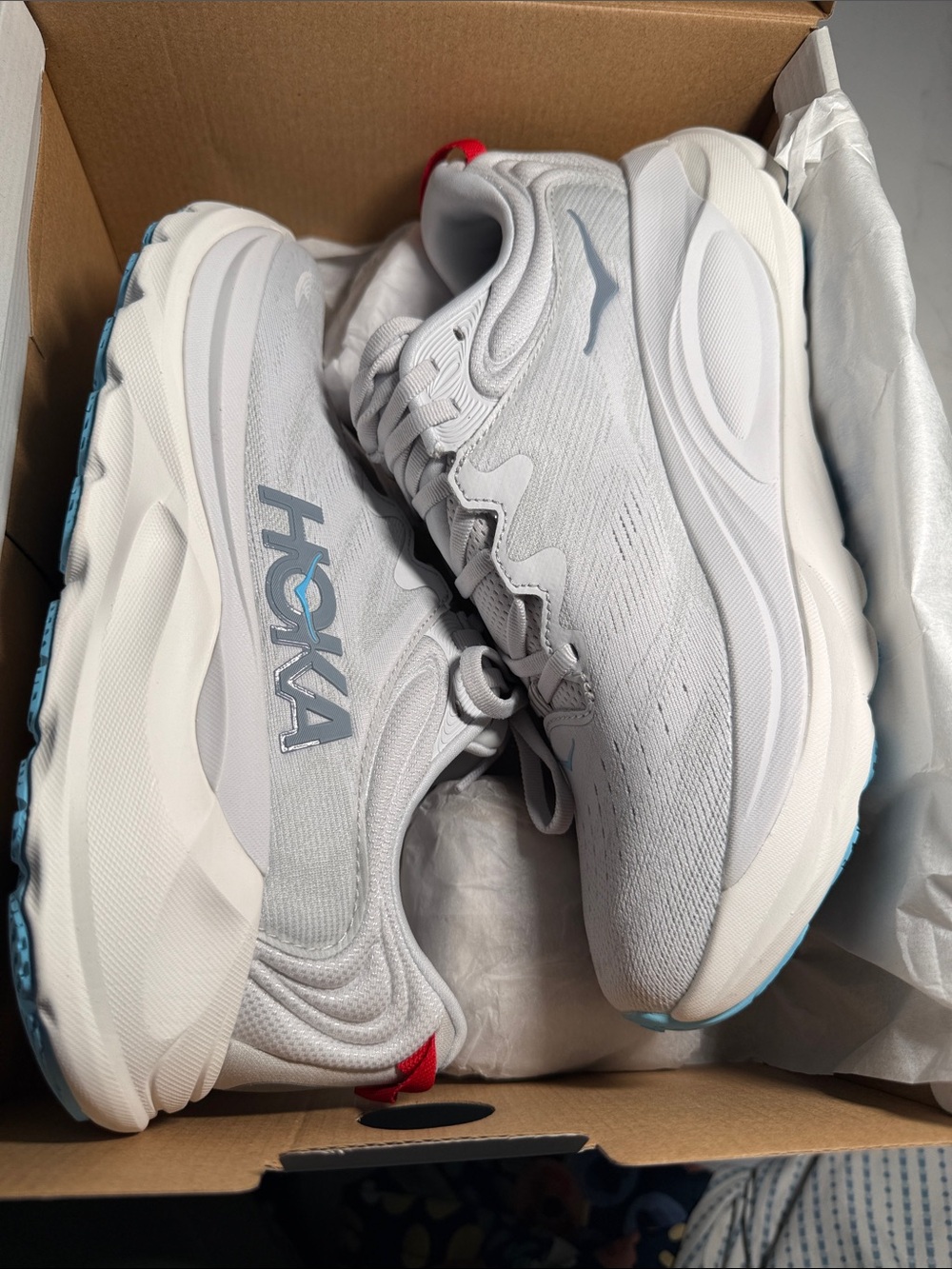Hoka women’s White Gray Sneakers with Red Heel Tab and Light Blue Outsole